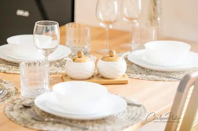a wooden table with white dishes and wine glasses at Modern Caribbean Stay Coral Azul 301 in La Laguna