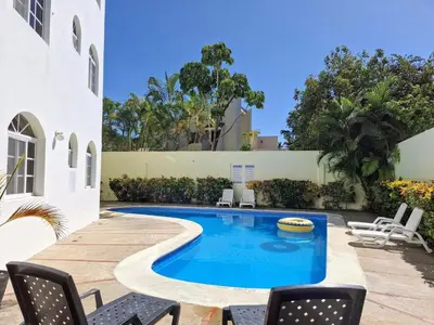 a swimming pool in a yard with chairs at 2-Bedroom Beach Apartment 50m from the Sea and Pool in San Felipe de Puerto Plata