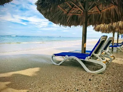 two lounge chairs under an umbrella on the beach at 2-Bedroom Beach Apartment 50m from the Sea and Pool in San Felipe de Puerto Plata