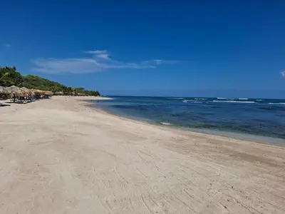 a sandy beach with umbrellas and the ocean at 2-Bedroom Beach Apartment 50m from the Sea and Pool in San Felipe de Puerto Plata