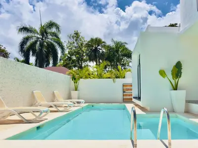 a swimming pool with chairs next to a white wall at Villa Las Terrenas Cosón minutes Pool and AC in Las Terrenas