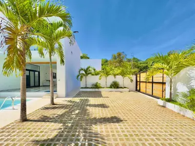 a courtyard with palm trees in front of a house at Villa Las Terrenas Cosón minutes Pool and AC in Las Terrenas