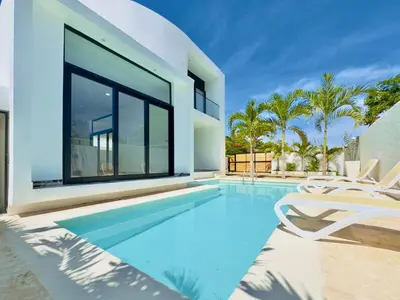 a swimming pool with two chairs and a house at Villa Las Terrenas walk to Punta Popy Pool, AC in Las Terrenas