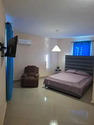 a bedroom with a bed and a chair and a television at Doña Minda Home in Naiboa