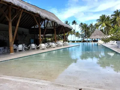 a large swimming pool with chairs and a building at Gorgeous large condo, quiet beachfront complex in Las Terrenas