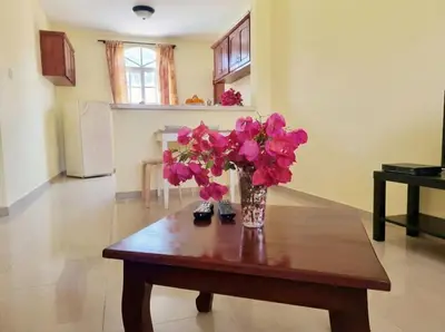 a vase of pink flowers on a wooden table at Ocean Breeze 2BR Apt 50m to Beach Pool AC in San Felipe de Puerto Plata