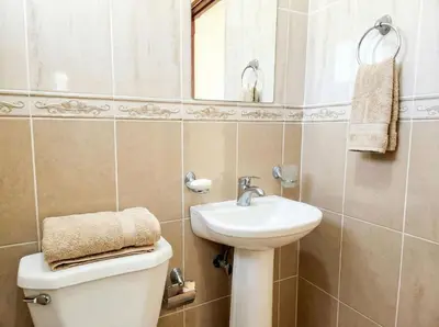 a bathroom with a sink and a toilet and a mirror at Ocean Breeze 2BR Apt 50m to Beach Pool AC in San Felipe de Puerto Plata