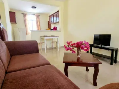 a living room with a couch and a table with flowers on it at Ocean Breeze 2BR Apt 50m to Beach Pool AC in San Felipe de Puerto Plata