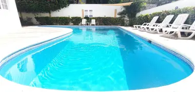 a swimming pool with chairs and a swimming pool at Ocean Breeze 2BR Apt 50m to Beach Pool AC in San Felipe de Puerto Plata