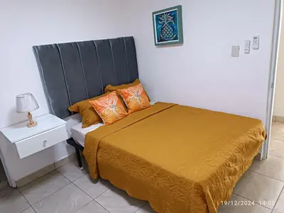 a bedroom with a bed with a black headboard and orange pillows at Casa de Huésped Romana in La Romana
