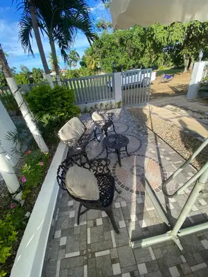 a patio with a table and chairs and palm trees at Brisas del mar in San Felipe de Puerto Plata