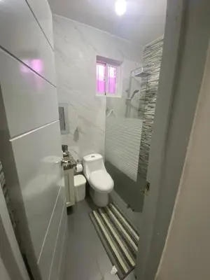 a white bathroom with a toilet and a window at Brisas del mar in San Felipe de Puerto Plata