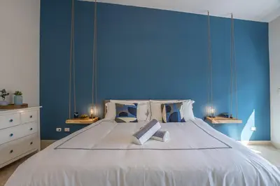 a bedroom with a large bed with a blue wall at Private Rooftop Penthouse Near Coson Beach Jacuzzi and BBQ in Las Terrenas