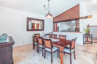 a dining room with a wooden table and chairs at Comfortable villa with garden view and 3 bedrooms in Cajuiles