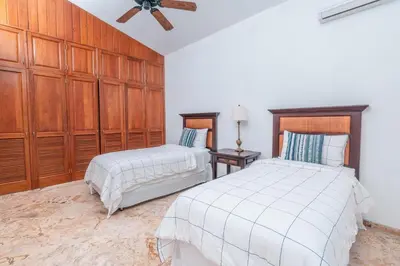 a bedroom with two beds and wooden cabinets at Comfortable villa with garden view and 3 bedrooms in Cajuiles