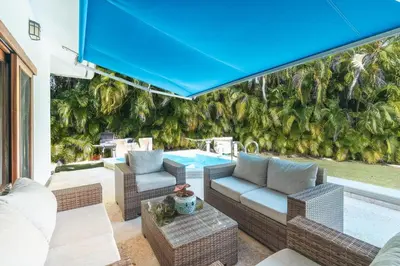 a patio with wicker furniture and a wall of trees at Comfortable villa with garden view and 3 bedrooms in Cajuiles