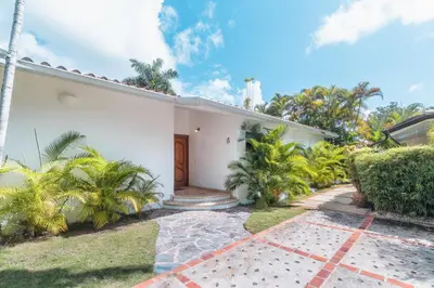 a white house with palm trees and a driveway at Comfortable villa with garden view and 3 bedrooms in Cajuiles