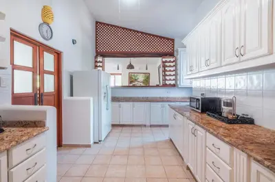 a kitchen with white cabinets and a white refrigerator at Comfortable villa with garden view and 3 bedrooms in Cajuiles