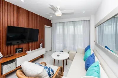 a living room with a white couch and a tv at Luxury 2BR, Private Jacuzzi, CanaRock Star in Punta Cana