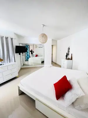a white bedroom with a large white bed with a red pillow at vista paraiso del mar in Villas del Mar