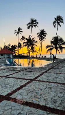 a sunset on a beach with palm trees and the ocean at vista paraiso del mar in Villas del Mar