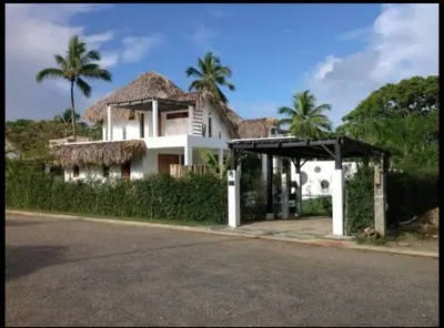 a large white house with a thatched roof at Villa Leon Azul in La Iglesia