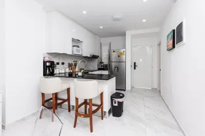 a kitchen with white walls and a counter and chairs at Luxury 2BR Private Jacuzzi CanaRock Star Punta Cana in Punta Cana