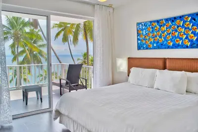 a bedroom with a bed and a balcony with palm trees at Ballena Bay View in Punta Balandra