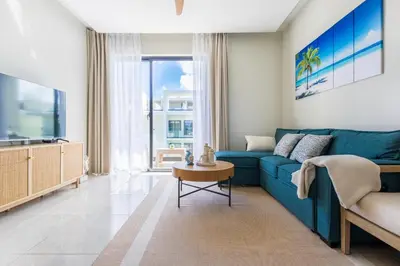 a living room with a blue couch and a tv at Stylish 1BR Apartment Near Bávaro Beach, Pool View in Punta Cana