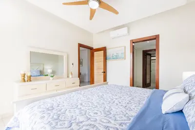 a bedroom with a blue bed and a ceiling fan at Stylish 1BR Apartment Near Bávaro Beach, Pool View in Punta Cana