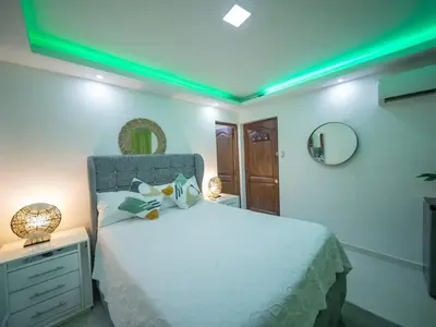 a bedroom with a white bed with a green lighting at Room in Sosua With Nice Jacuzzi in Sosúa