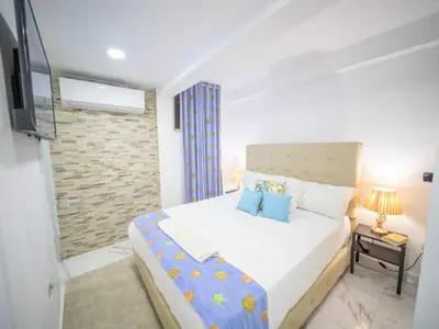 a bedroom with a white bed and a television at Studio In Sosua Center Strip Zone in Sosúa