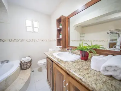 a bathroom with a sink and a mirror and a tub at Spacious 1BR APT in Sosua strip in Sosúa