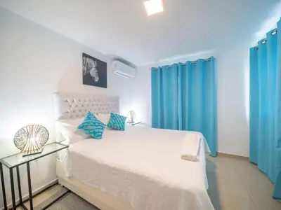 a bedroom with a white bed and blue curtains at Cozy & Central 3BR Apt Secure & Comfortable in Sosúa
