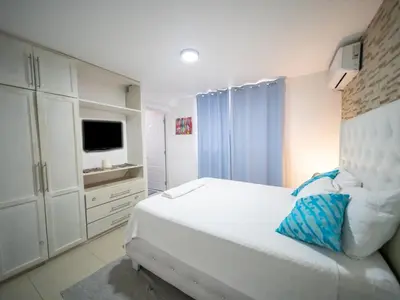 a white bedroom with a bed and a television at Cozy & Central 3BR Apt Secure & Comfortable in Sosúa
