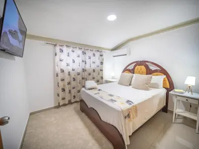 a bedroom with a large bed and a desk at Stylish 1BR Near Beach & Main Strip Sosua in Sosúa