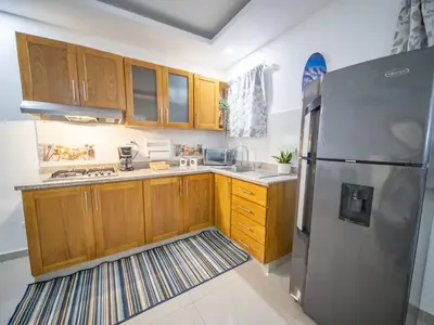 a kitchen with wooden cabinets and a stainless steel refrigerator at Stylish 1BR Near Beach & Main Strip Sosua in Sosúa