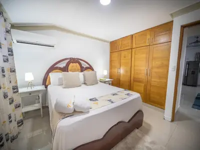 a bedroom with a large white bed and wooden cabinets at Stylish 1BR Near Beach & Main Strip Sosua in Sosúa
