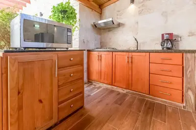 a kitchen with wooden cabinets and a microwave at Room in the center with Outdoor Jacuzzi in Sosúa