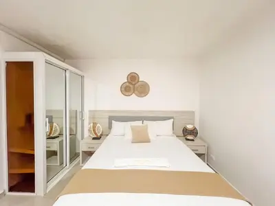 a white bedroom with a large bed and mirrors at Secure and Central 2BR Apt in Sosúa