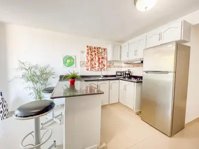 a kitchen with white cabinets and a stainless steel refrigerator at Secure and Central 2BR Apt in Sosúa