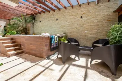 a patio with chairs and a table and a brick wall at Getaway room with shared Jacuzzi in the center in Sosúa