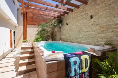a swimming pool in a patio with a brick wall at Getaway room with shared Jacuzzi in the center in Sosúa