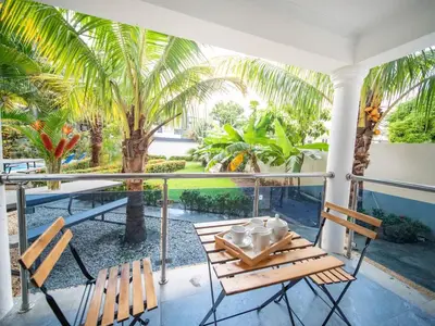a porch with two chairs and a table and palm trees at Affordable 1BR APT in Sosua Center - Strip Zone in Sosúa