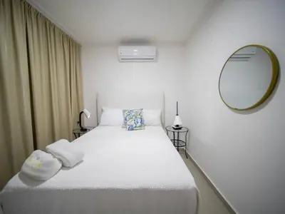 a bedroom with a large white bed with a mirror at 2BR APT in Sosua Center Strip zone in Sosúa