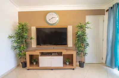 a living room with a television and a clock on the wall at Garden Condos APT 35 - Affordable 1BR APT in Sosua in Sosúa