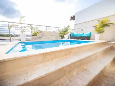 a swimming pool with stairs leading to a house at 4BR Penthouse with Rooftop Pool in Sosua strip in Sosúa