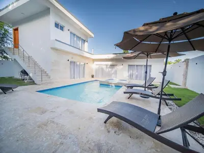 a swimming pool with two chairs and an umbrella at First class 4BR KING SIZE Villa in Sosua town in Sosúa