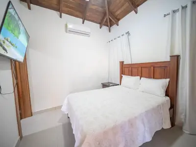 a bedroom with a white bed and a flat screen tv at Modern 5BR Private Villa in Sosua center in Sosúa