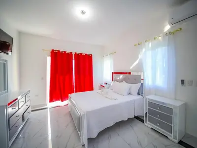 a bedroom with a white bed and a red curtain at 8BR Private Villa in Sosua 2 mins from Nightlife in Sosúa